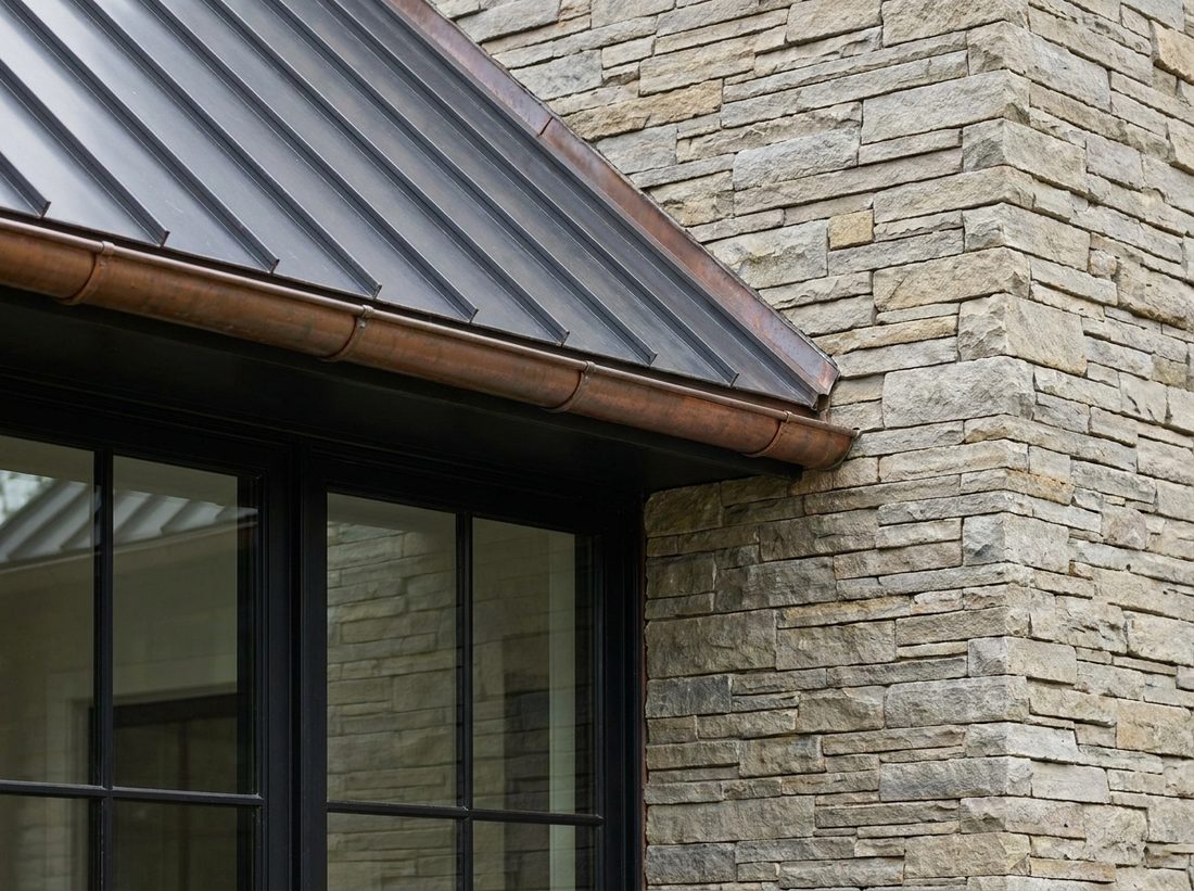 Premium exterior detail: metal roof eave, copper gutter, stone and black-trimmed window.